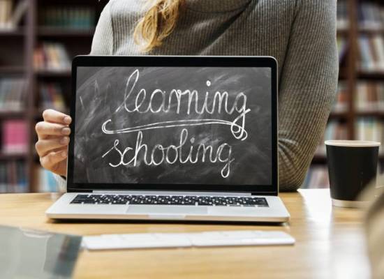 Person in gray sweater using black laptop computer